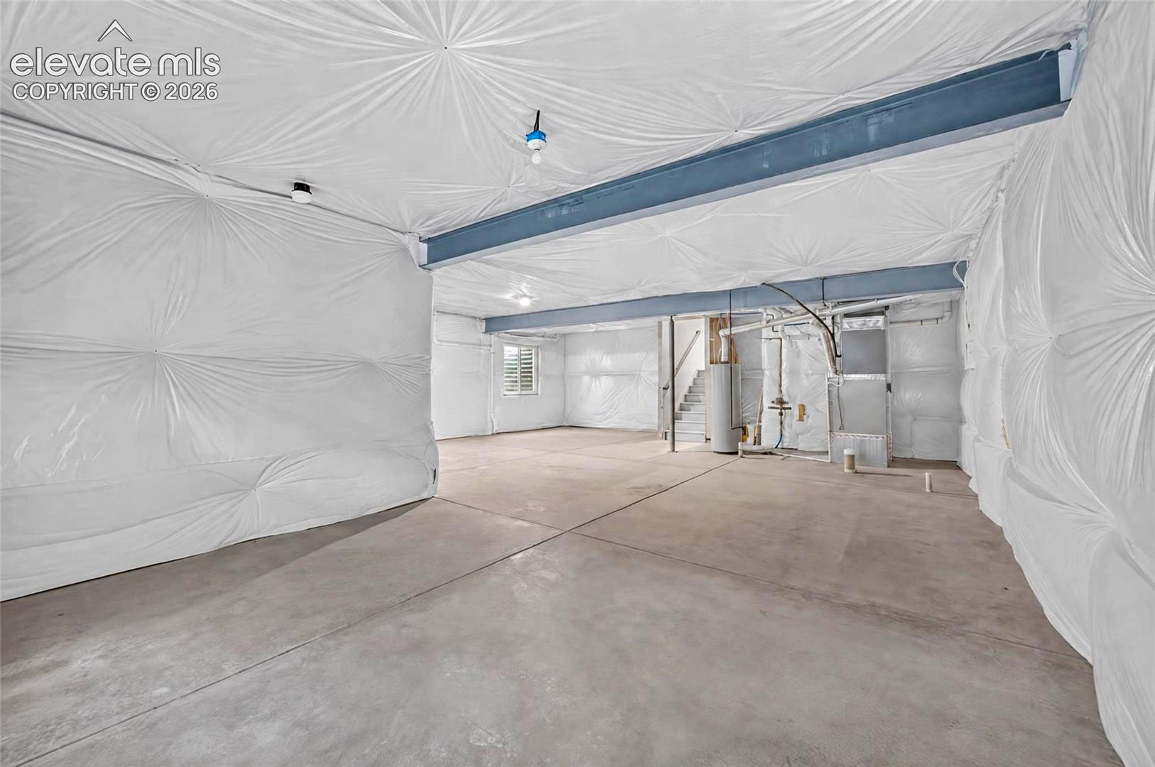 Expansive unfinished space featuring concrete flooring, exposed structural beams, and interior insulation