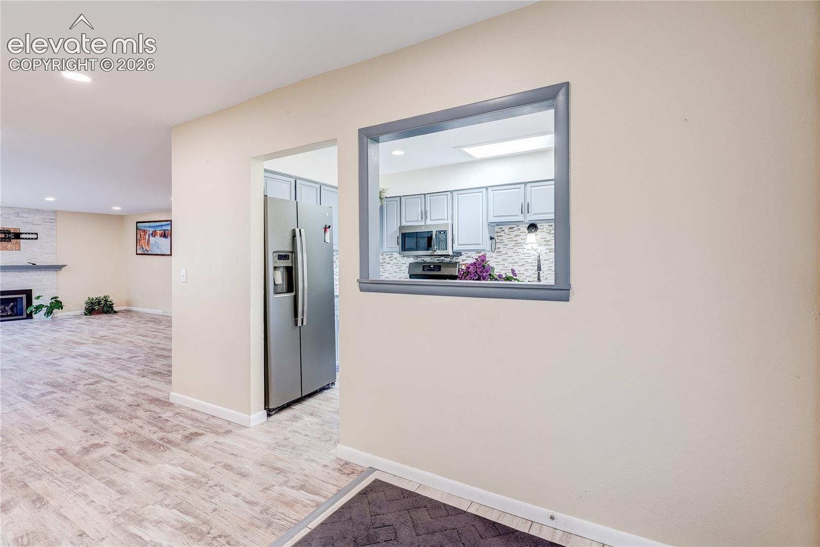 Pass-through window with grey trim, wood-finish flooring, recessed lighting, and built-in cabinetry