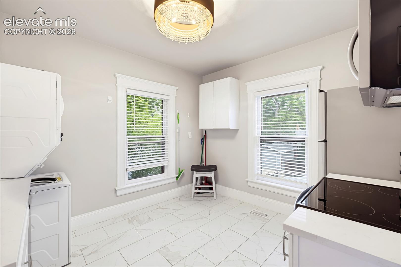 White tile flooring, dual windows with white trim, built-in white cabinetry, and a modern ceiling light fixture