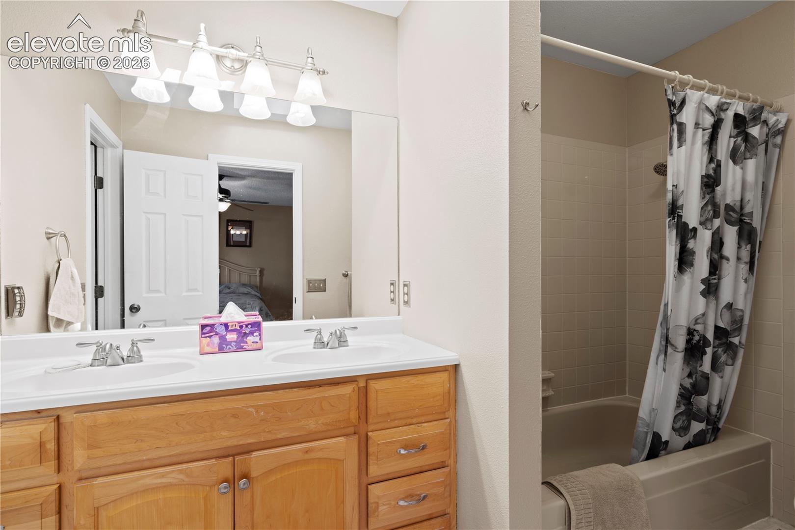 Dual vanity with integrated sinks, wood-finish cabinetry, and a full-width mirror