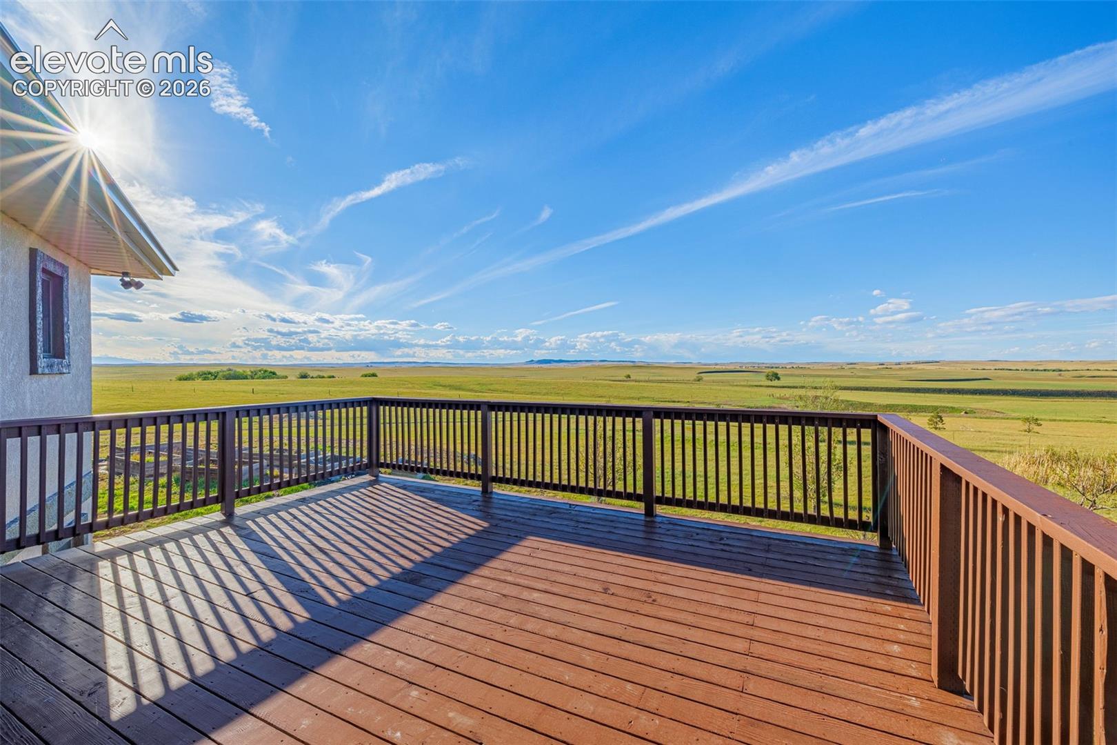 Expansive outdoor deck with wood-finish flooring and a full railing system, offering panoramic landscape scenery
