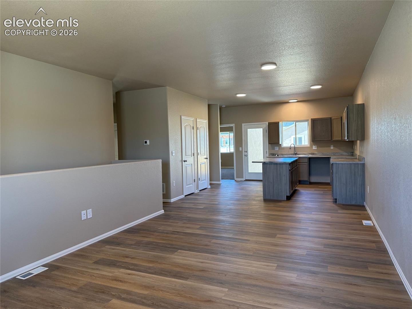 Open-concept living area featuring wood-finish flooring, recessed lighting, and neutral wall tones