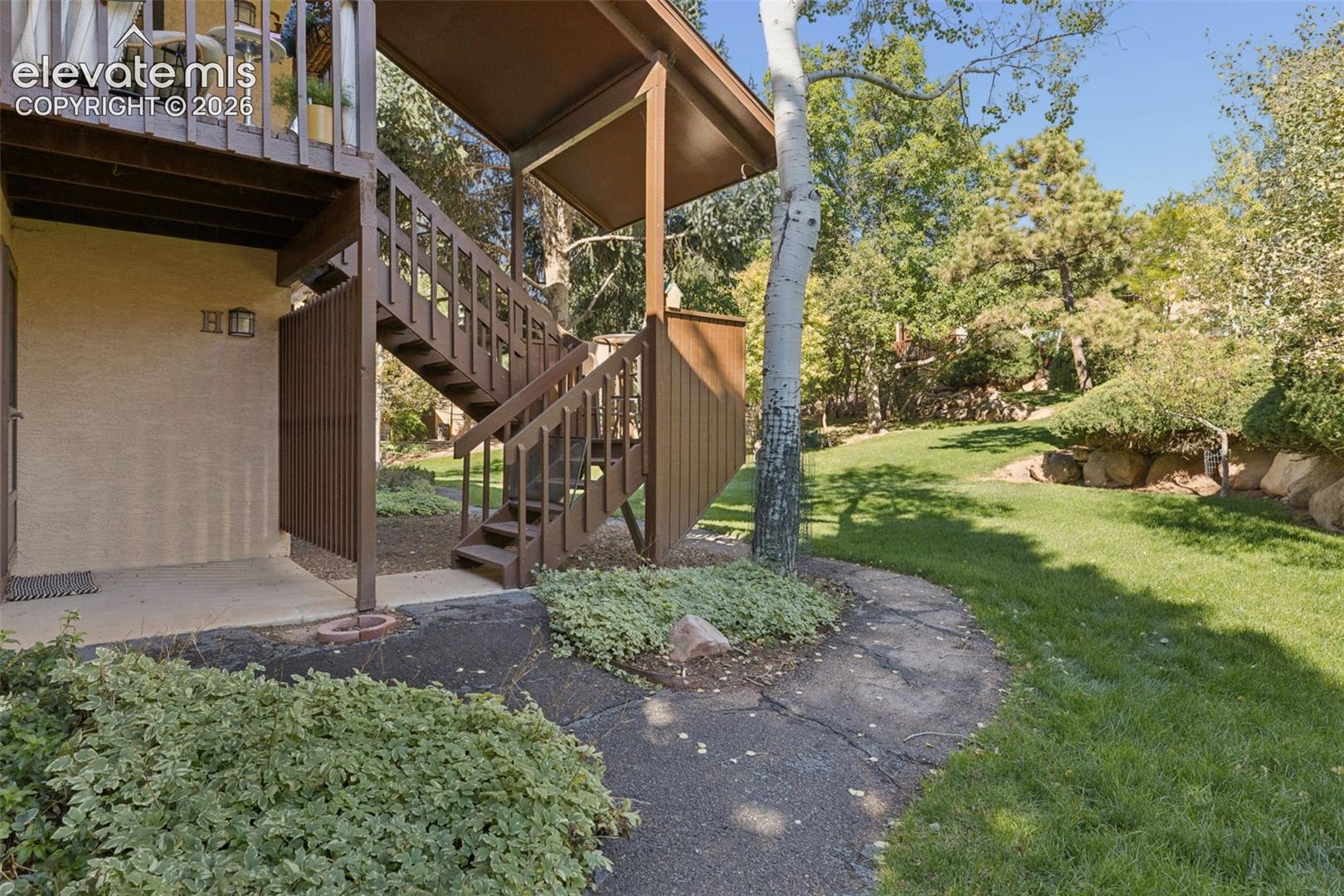 Two-story exterior with a ground-level patio, upper-level balcony, and exterior staircase