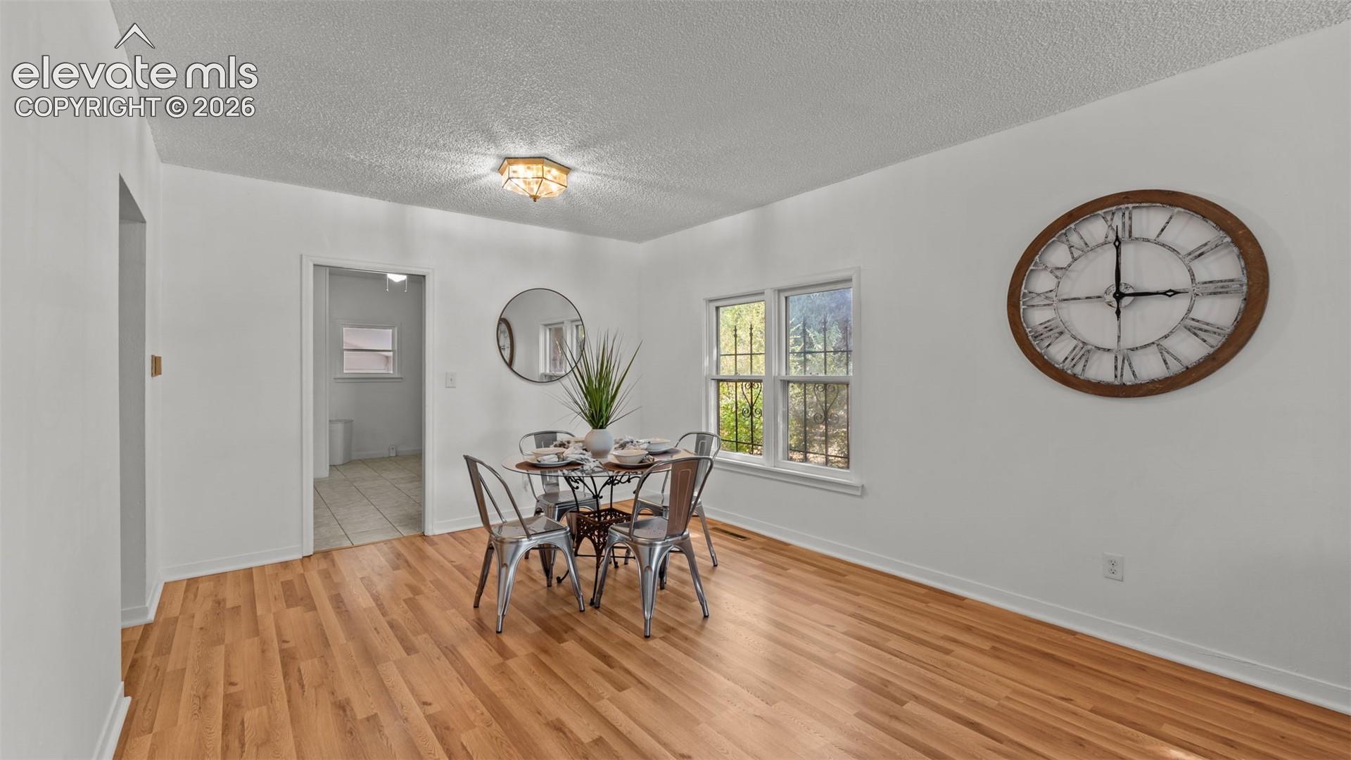 Wood-finish flooring, white painted walls, and a multi-pane window