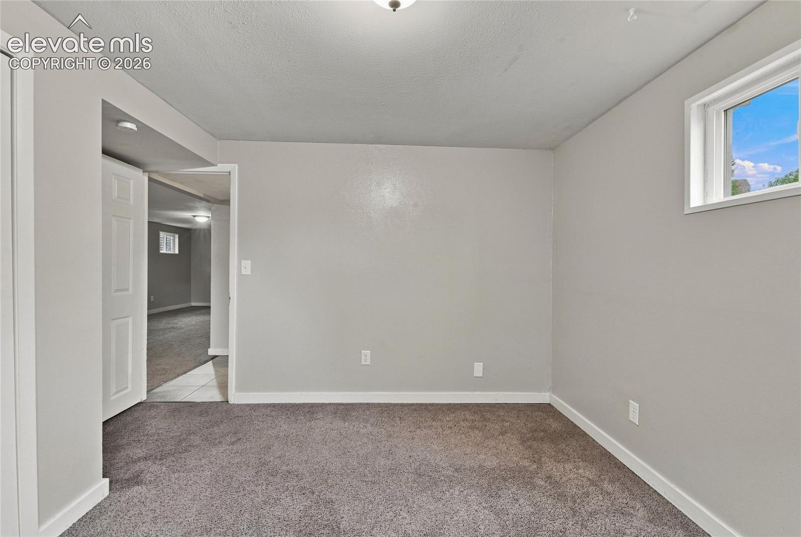 Basement bedroom with carpet flooring, white trim, and two windows provide natural light