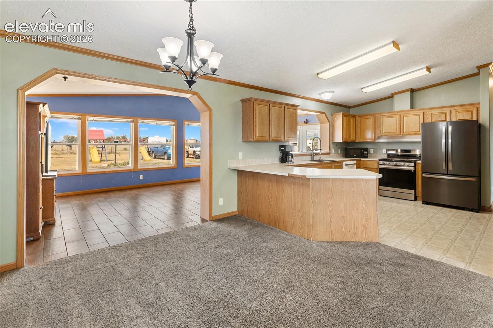 Spacious kitchen featuring wood-finish cabinetry, stainless steel appliances, a light-toned countertop, and a breakfast bar