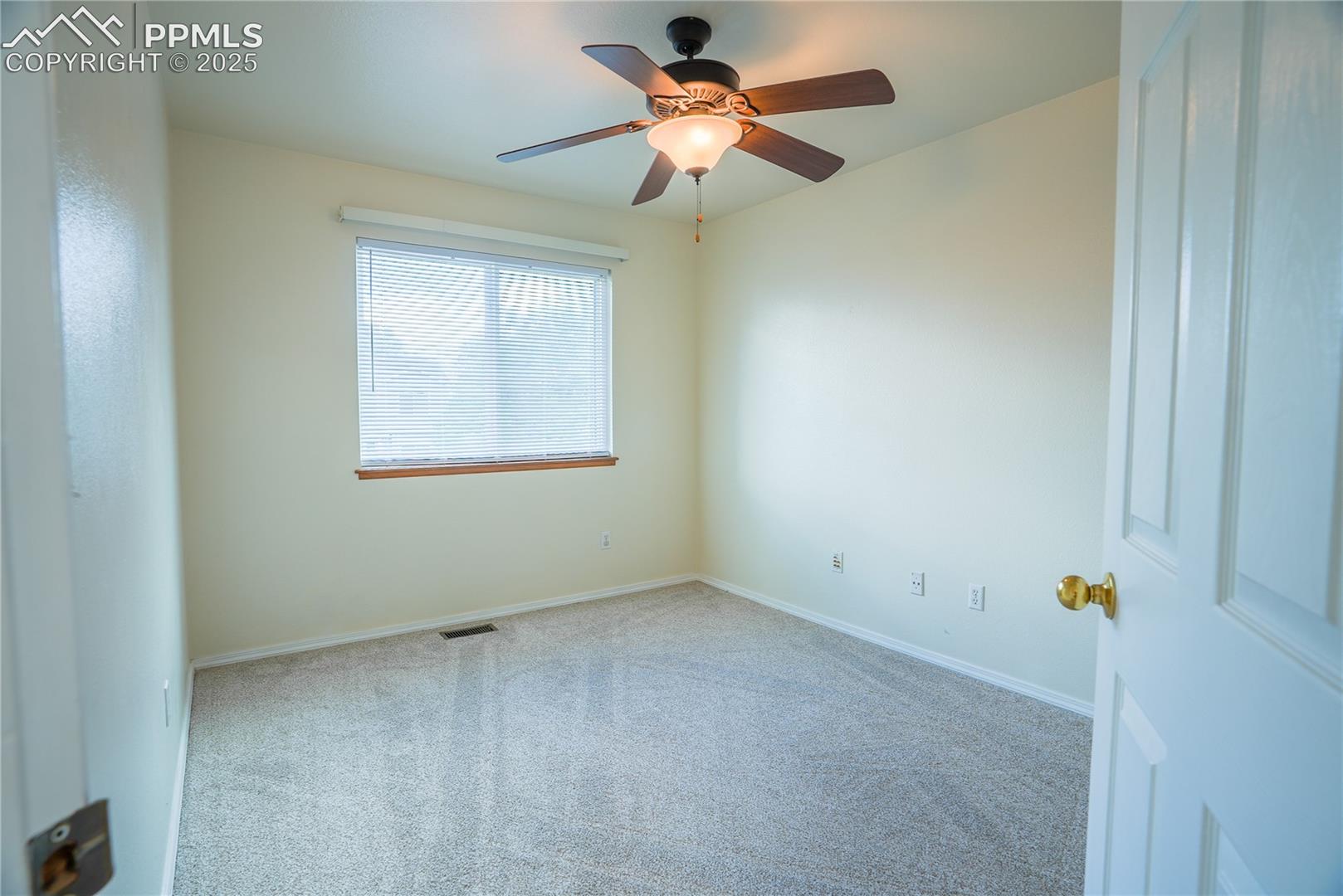 Carpeted spare room with baseboards and ceiling fan