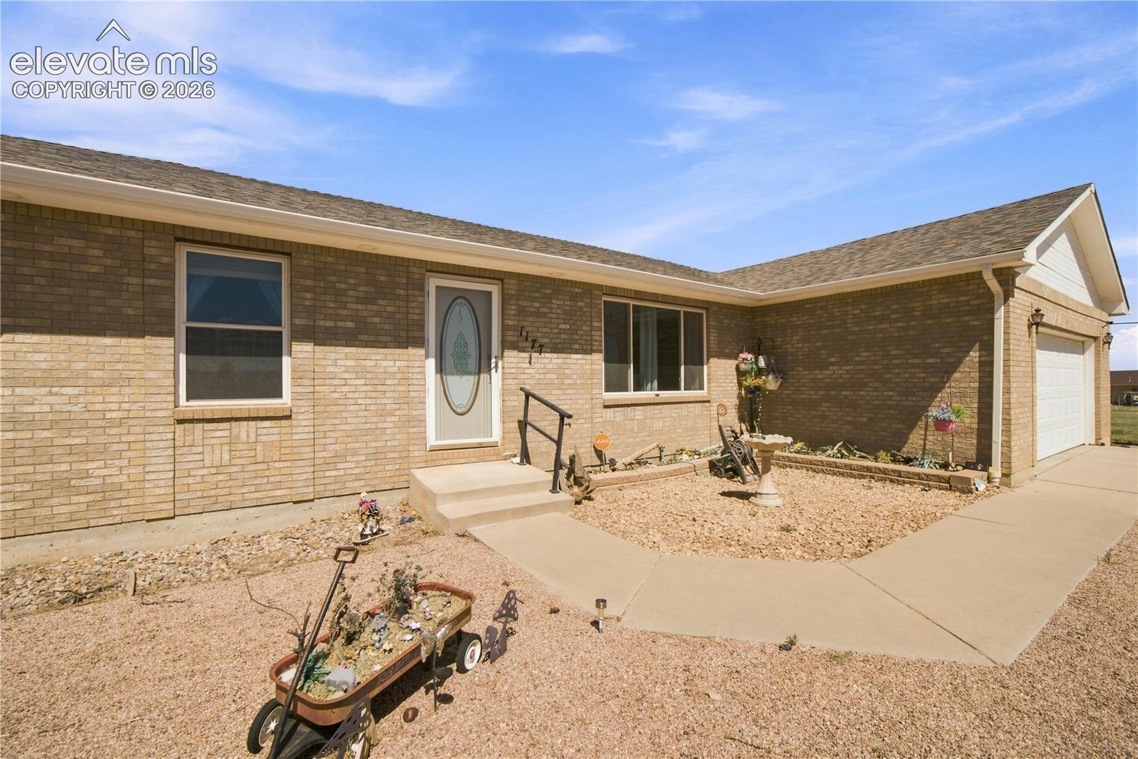 Brick exterior with a covered entryway, attached two-car garage, and a concrete pathway