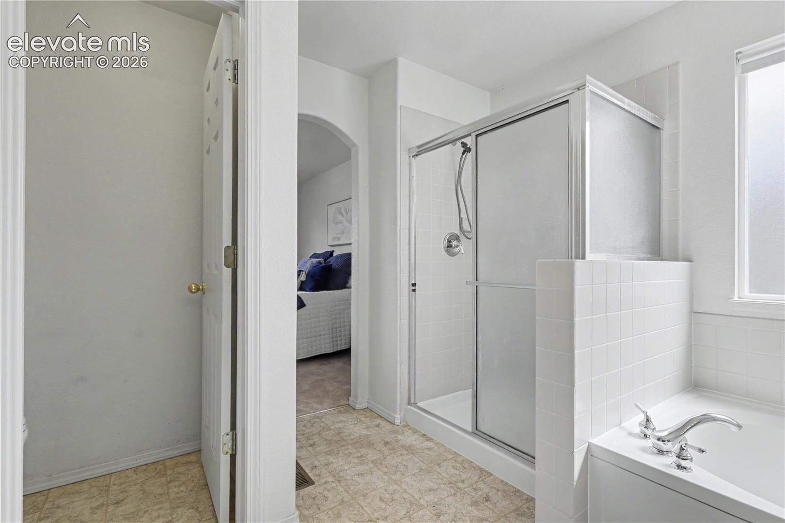 Shower with sliding glass enclosure, white subway tile surround, and chrome fixtures