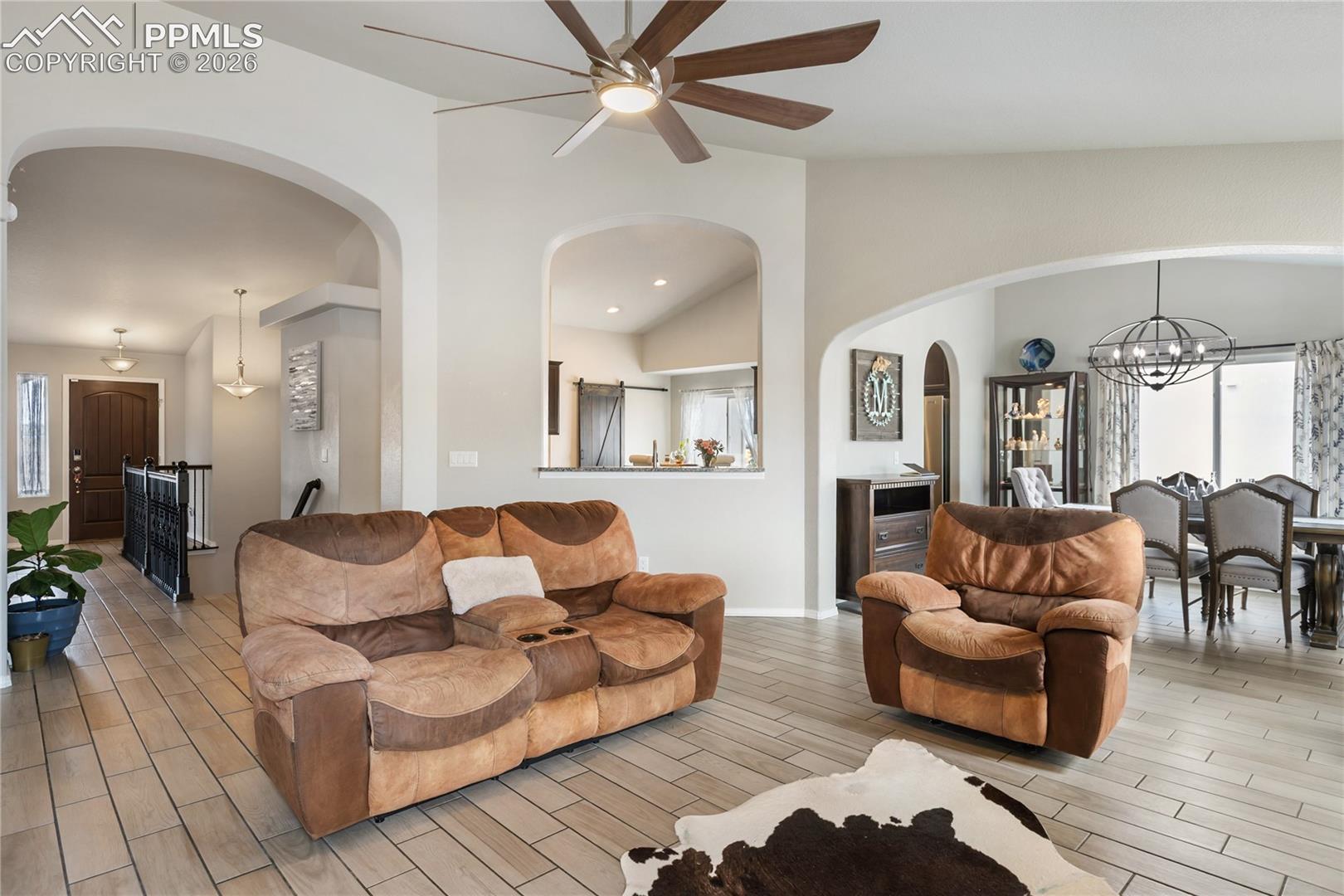Living area featuring ceramic tile flooring, vaulted ceilings, and a ceiling fan