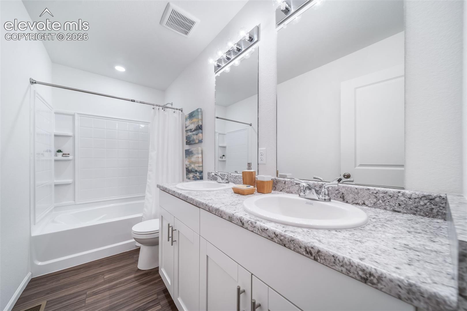 Dual vanity with stone-finish countertop, white cabinetry, and undermount sinks
*photos of a model home*