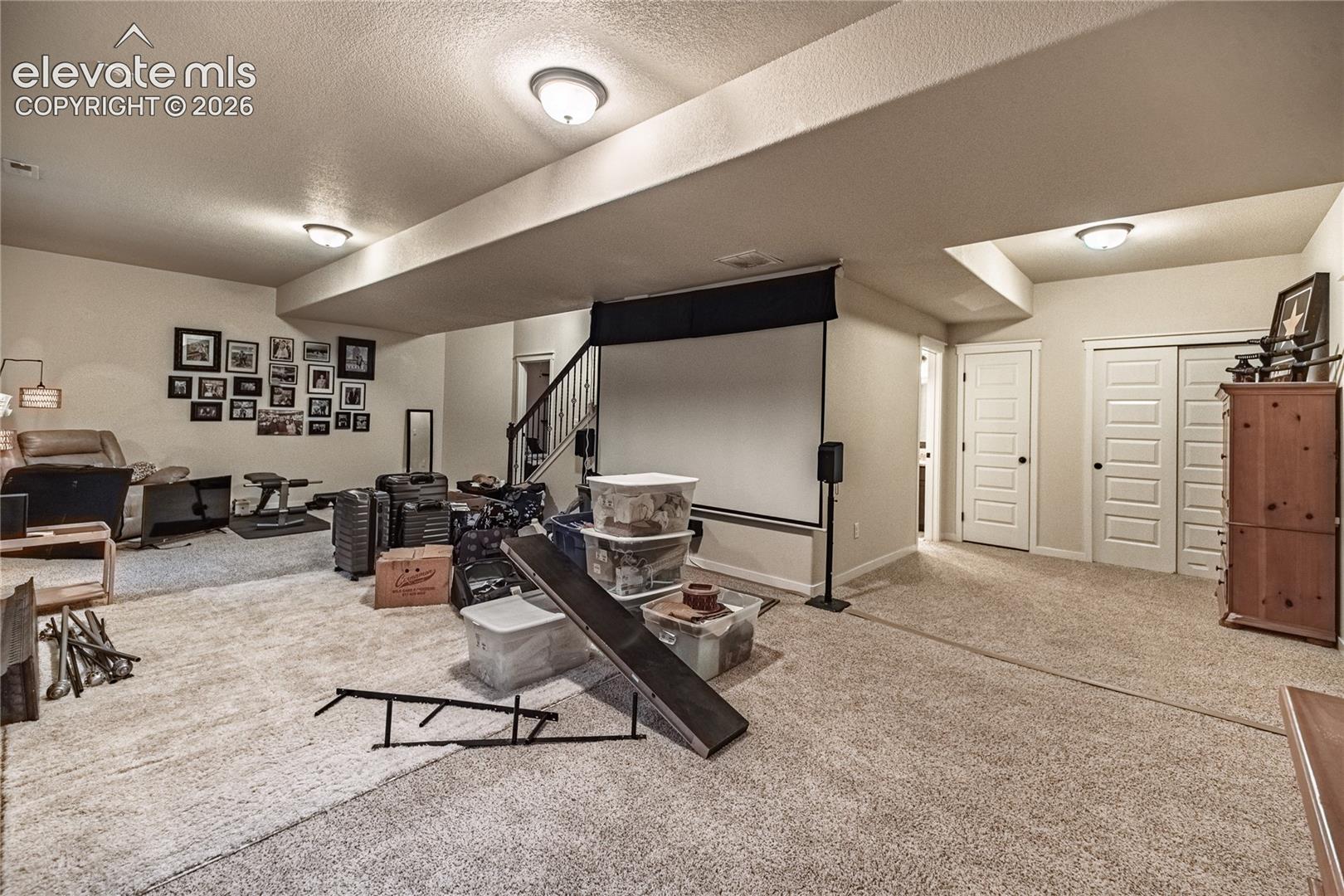 Open-concept interior featuring neutral wall tones, wall-to-wall carpeting, flush-mount ceiling lighting, and multi-panel interior doors