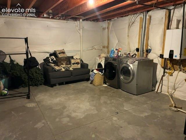 Unfinished basement space featuring exposed wood joist ceilings, concrete flooring, insulated wall panels, and a wall-mounted tankless water heater