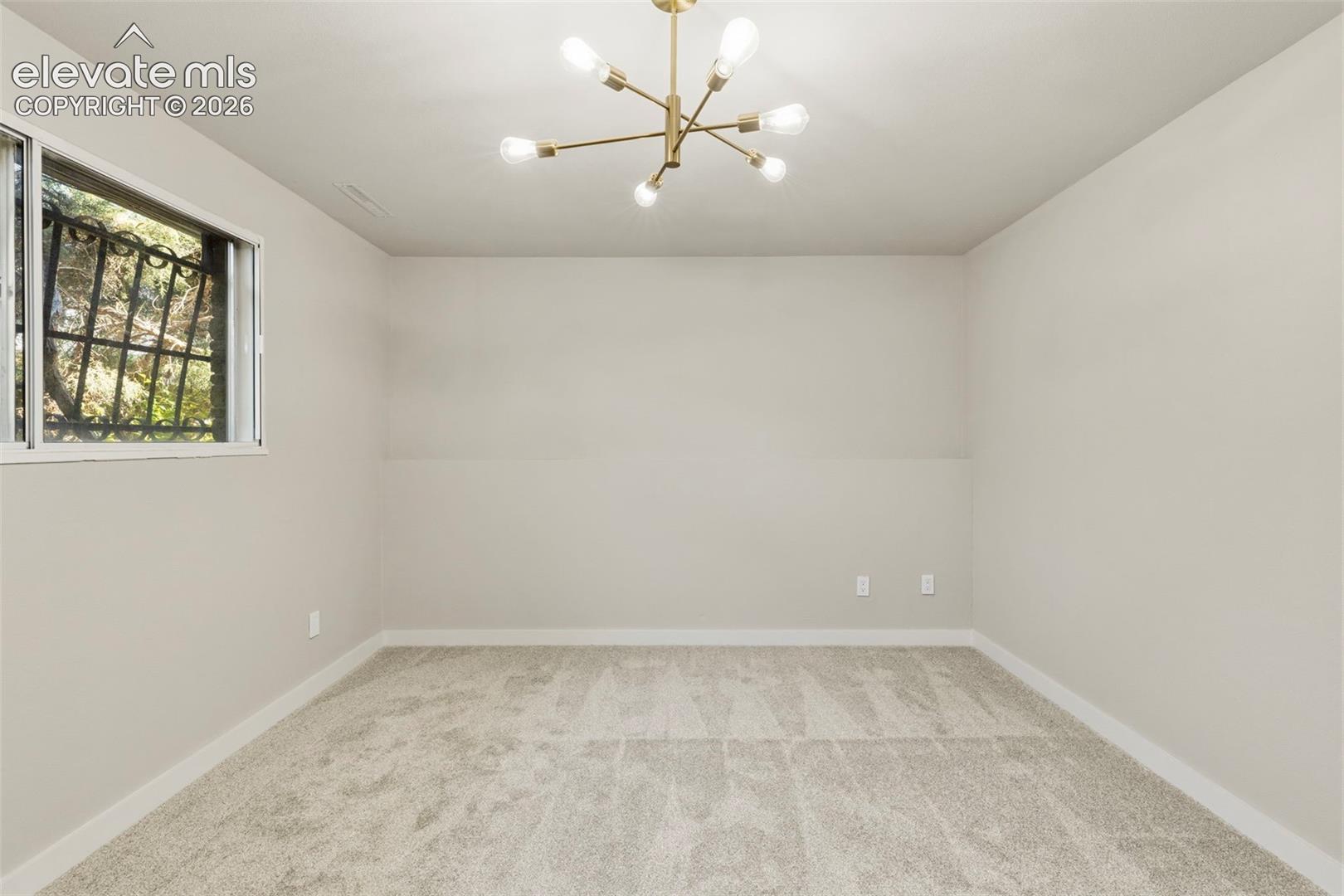 Spacious room featuring new carpeting, a contemporary sputnik chandelier, and light neutral wall tones