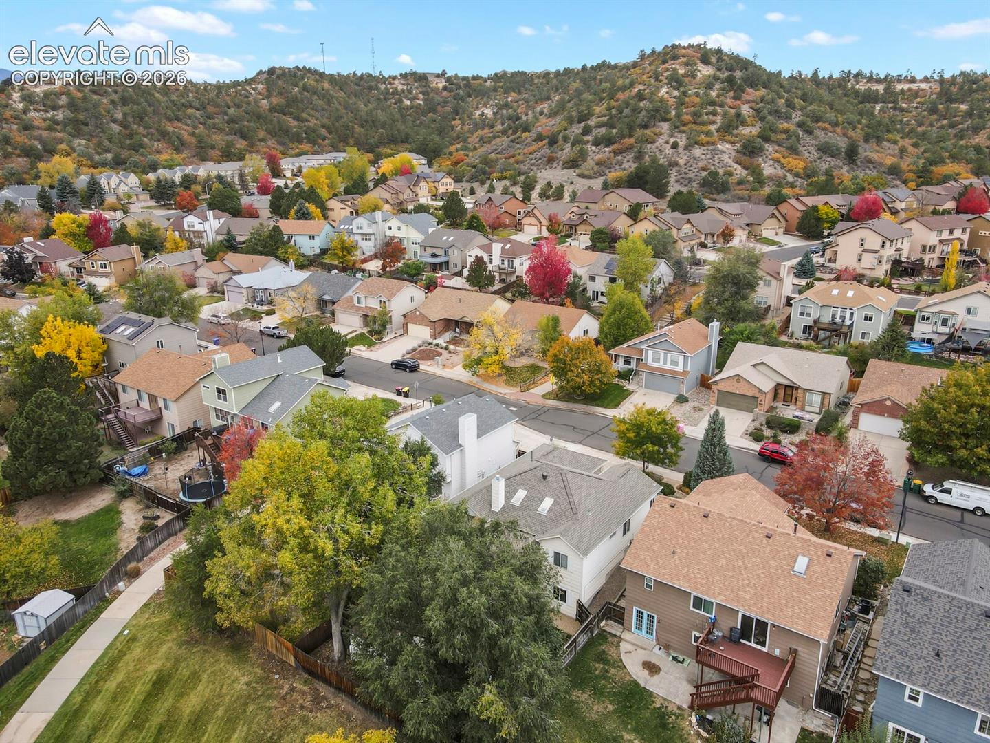Aerial perspective featuring mountainous topography, mature trees, and a residential neighborhood with paved streets