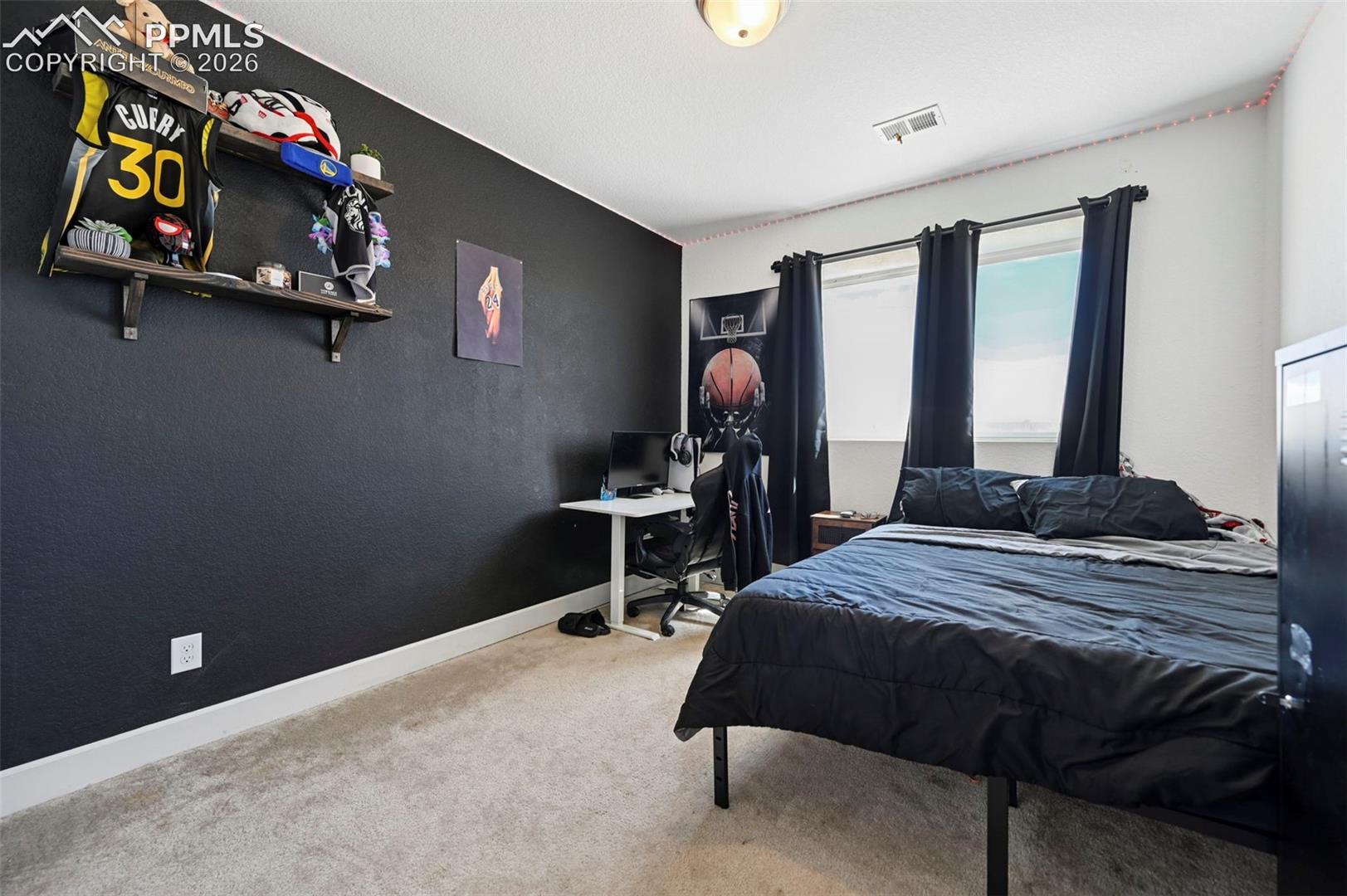 Carpeted room with a dark accent wall, white baseboards, and two windows
