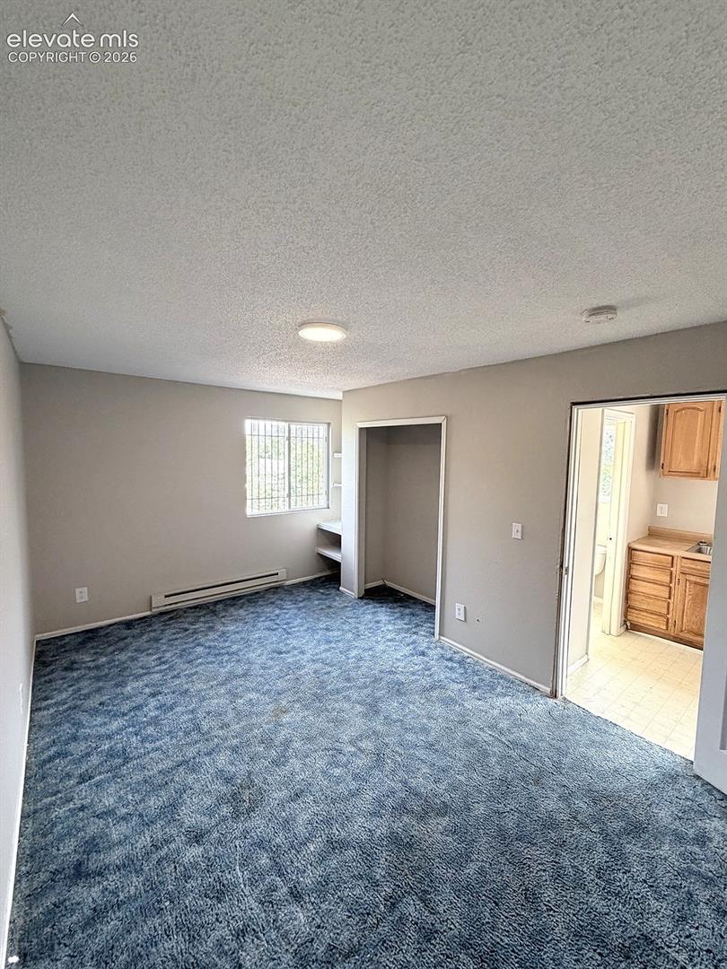 Wall-to-wall carpeting, built-in shelving, and a window with security bars