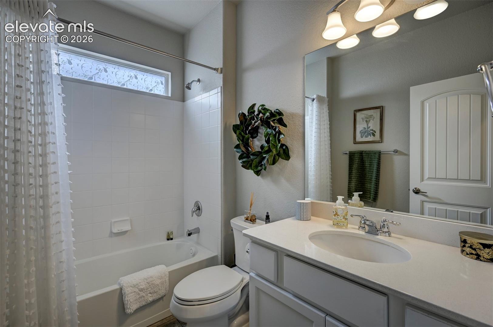 White vanity with an integrated sink, polished chrome faucet, and overhead vanity lighting