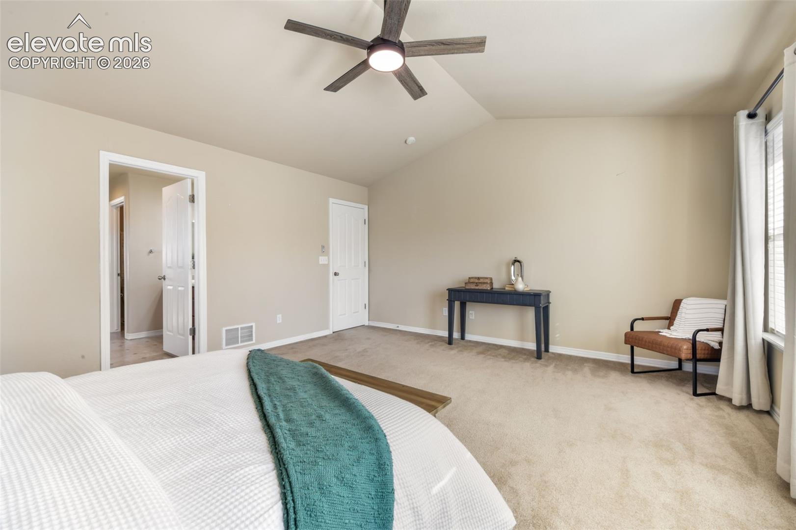 Vaulted ceiling with an attached ceiling fan, neutral carpet flooring, and a window with blinds and curtains