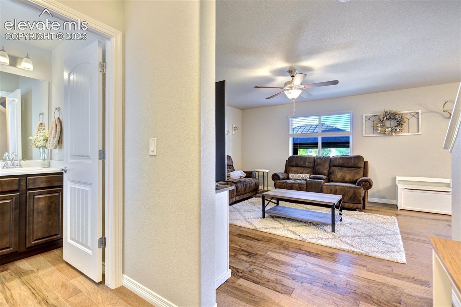 Wood-finish flooring, dark wood cabinetry with chrome hardware, ceiling fan with light kit, and multi-pane window