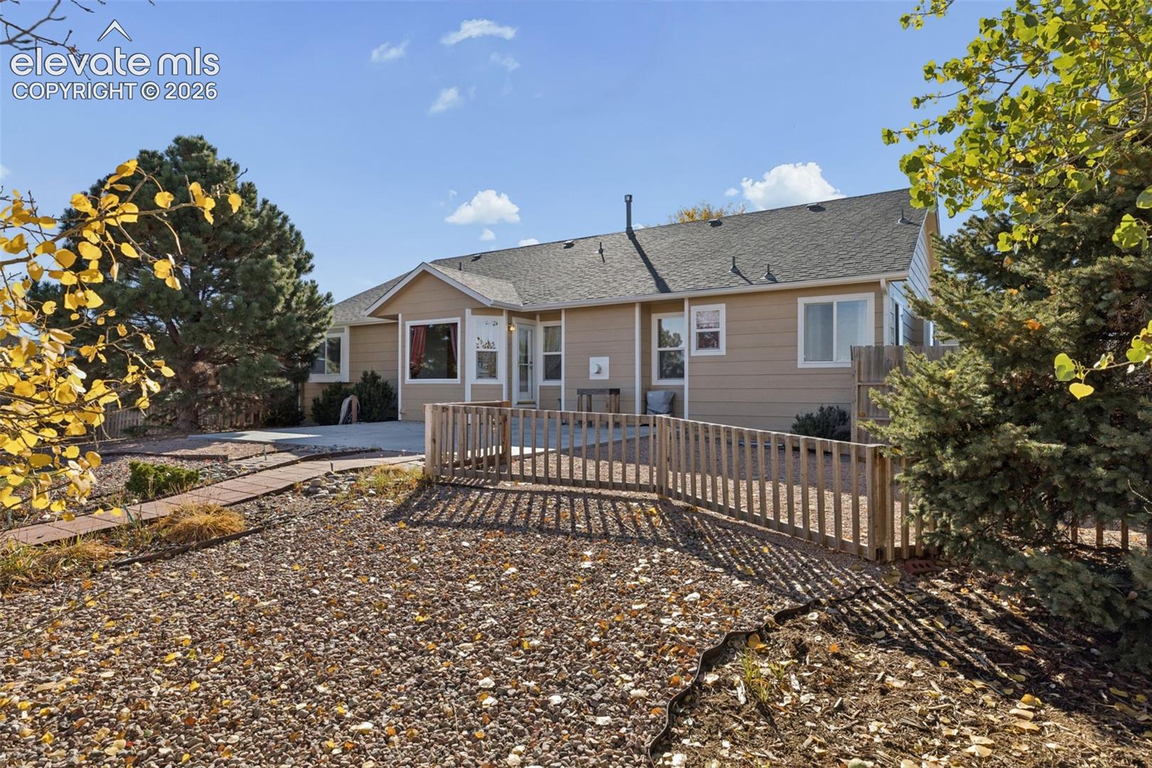Exterior siding with concrete patio, gravel landscaping, and wood-slat perimeter fencing