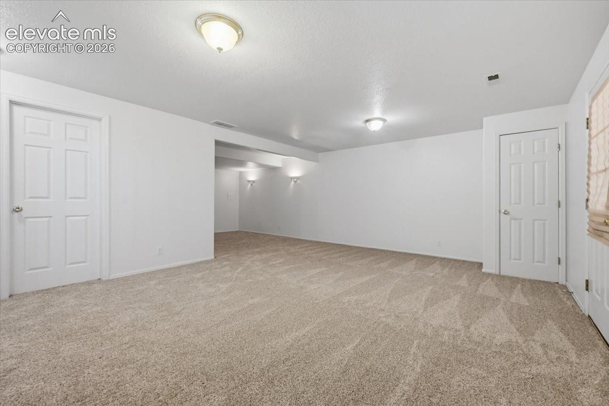 Expansive carpeted area with neutral walls and multiple panel doors