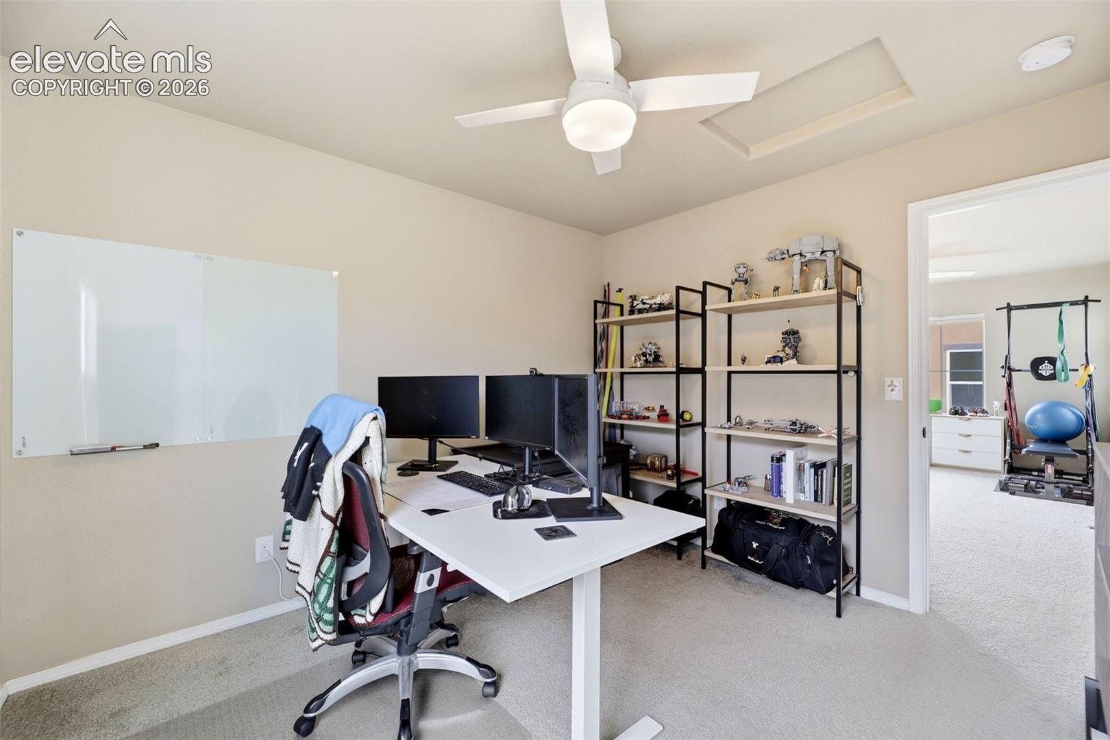 White ceiling fan with integrated lighting, wall-mounted whiteboard, and light-colored carpeting