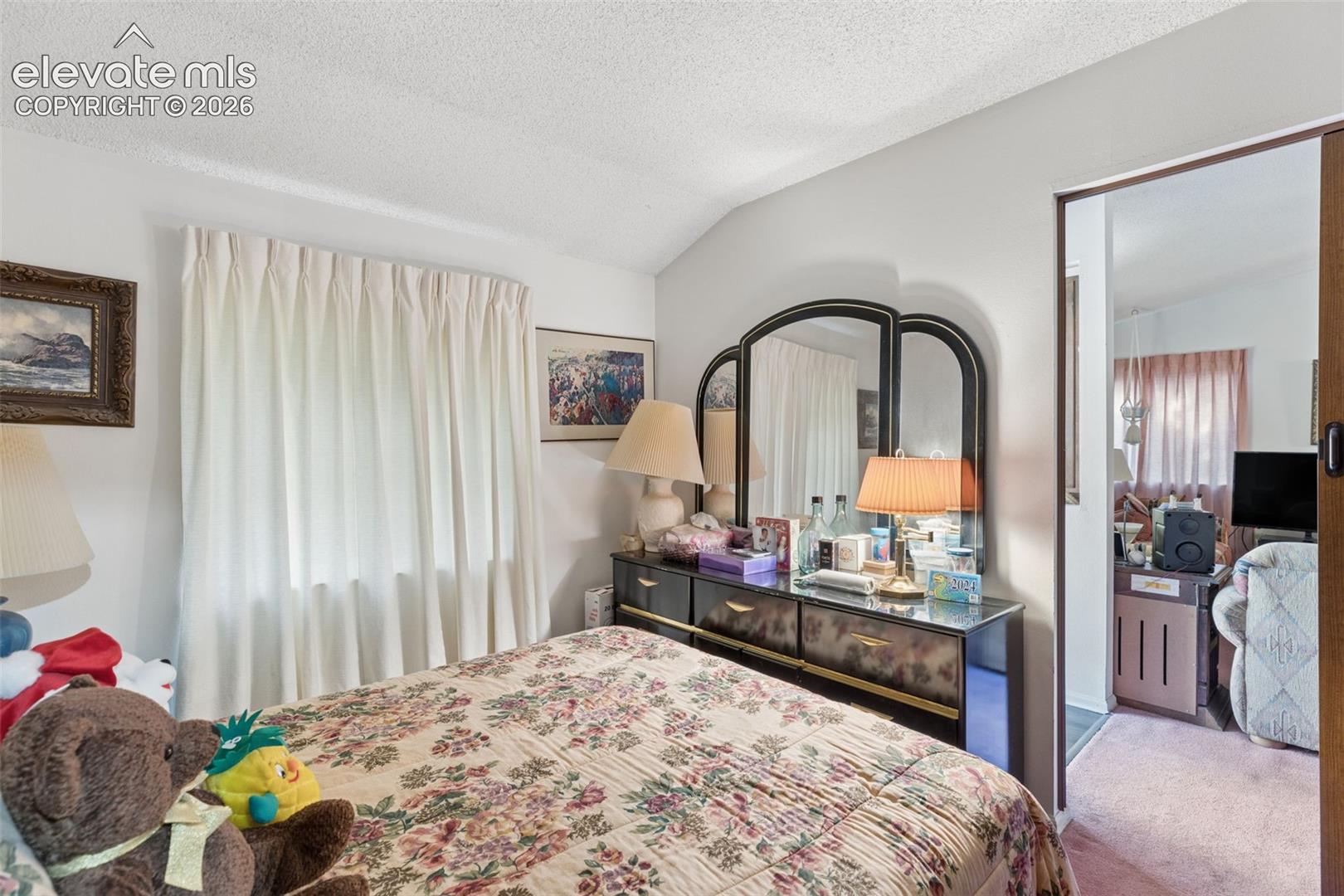 Bedroom featuring neutral wall paint, a vaulted ceiling, and sliding pocket door entry