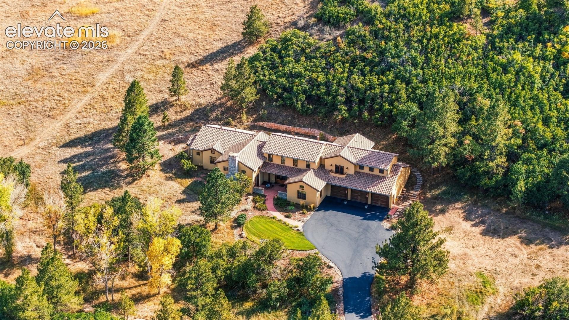 Expansive property featuring a multi-level structure with a gabled roof, attached garages, and a paved driveway