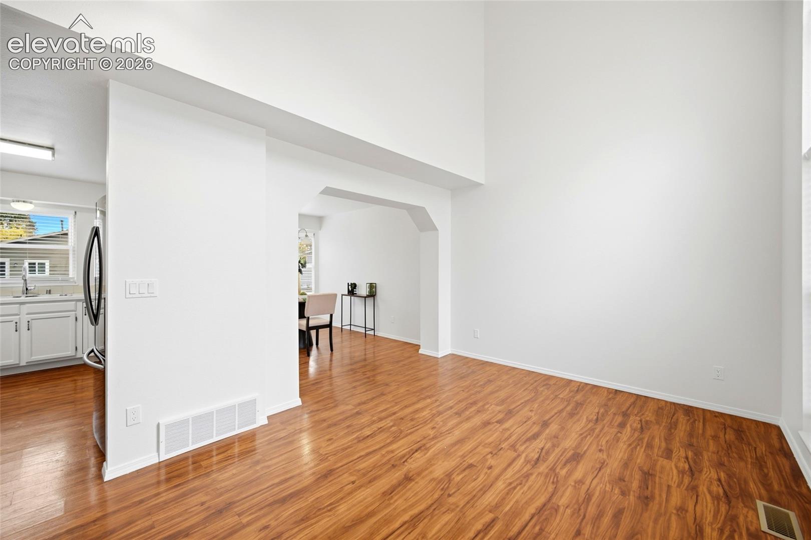 High-ceilinged interior featuring wood-finish flooring and an arched architectural opening