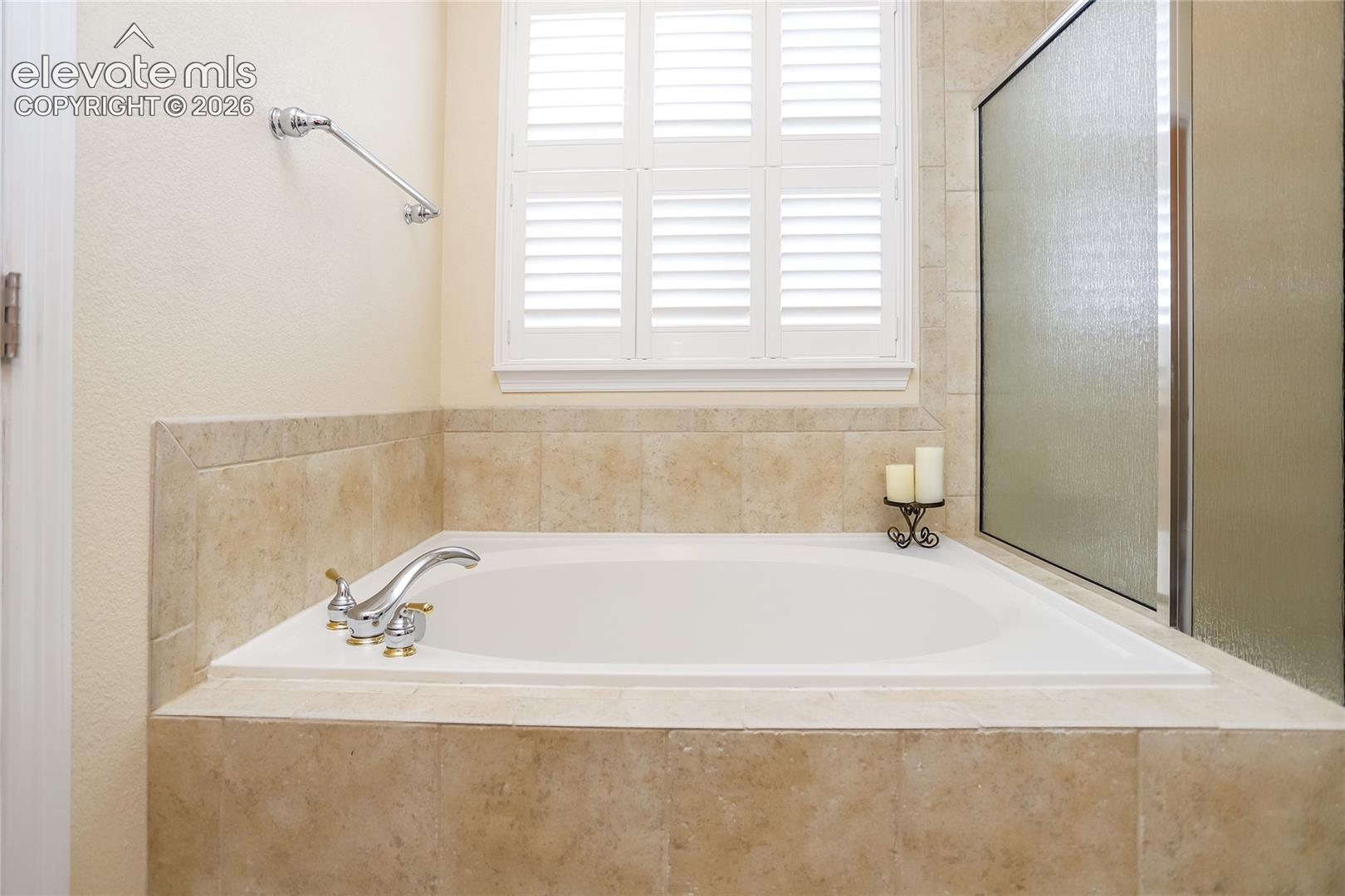 Built-in soaking tub with a tiled surround and plantation shutters!