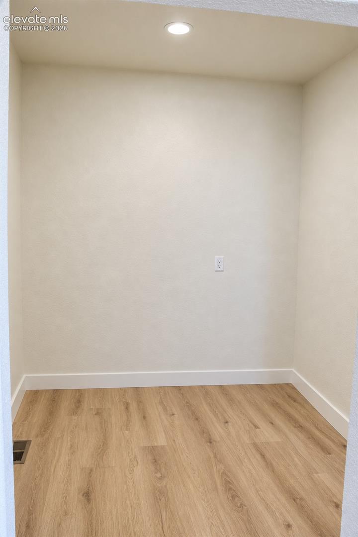 Recessed ceiling light, neutral wall color, wood-finish flooring, white trim