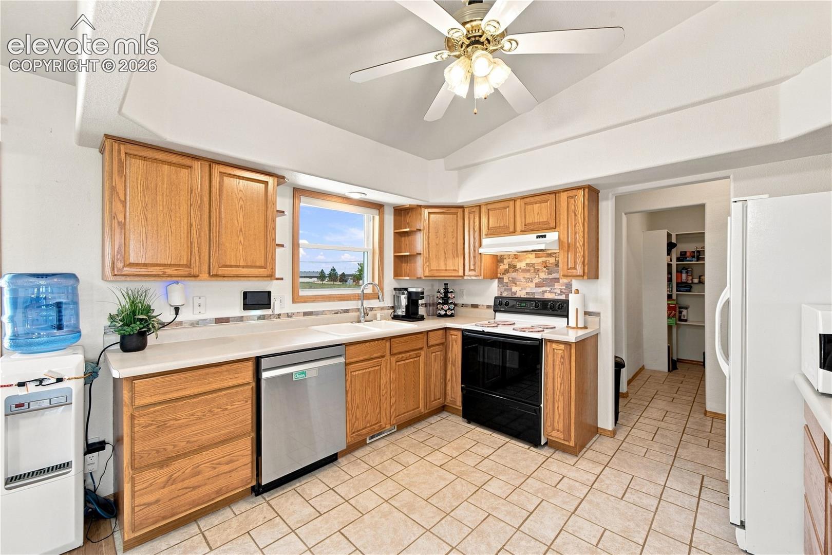 Kitchen featuring wood cabinetry, light-toned countertops, tile flooring, and a ceiling fan