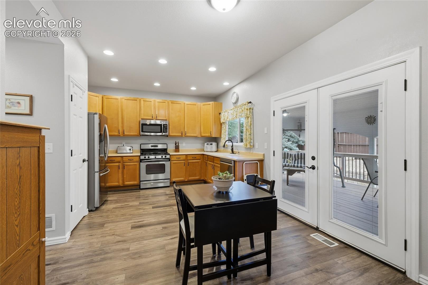 Kitchen with wood-finish flooring, recessed lighting, and stainless steel appliances. Kitchen walk-out to dreamy composite deck and wonderful outdoor living space