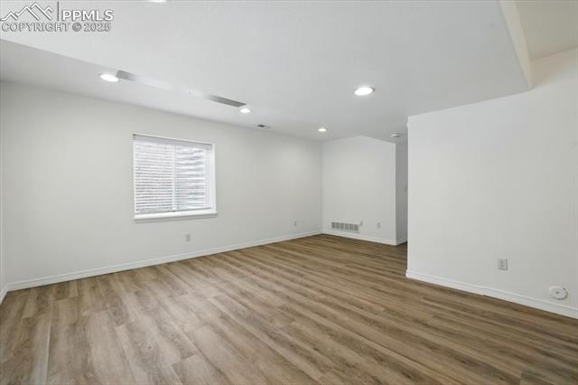 Empty room featuring recessed lighting, wood finished floors, and baseboards