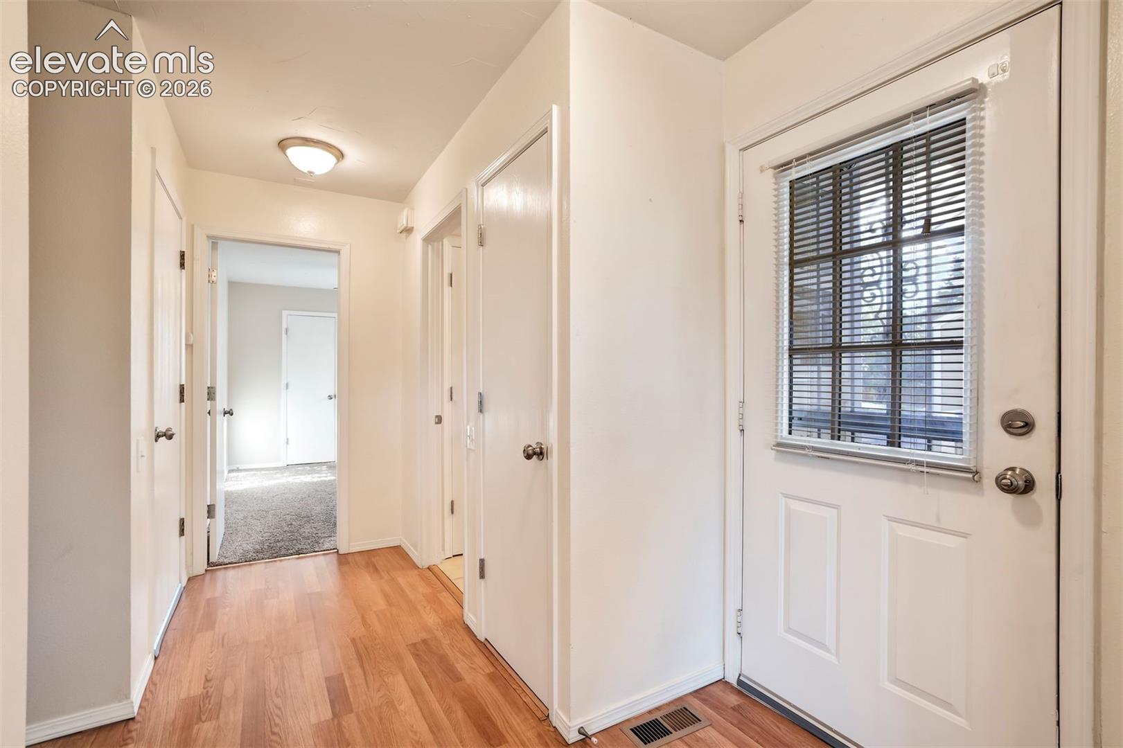 Entryway featuring wood-finish flooring, a white door with an integrated glass panel, and flush-mount ceiling lighting