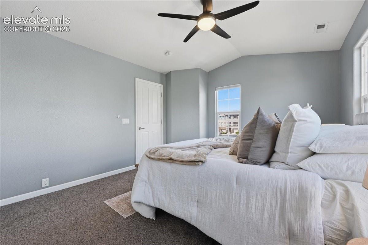 Vaulted ceiling featuring a ceiling fan with integrated lighting, a panel door, and carpet flooring
