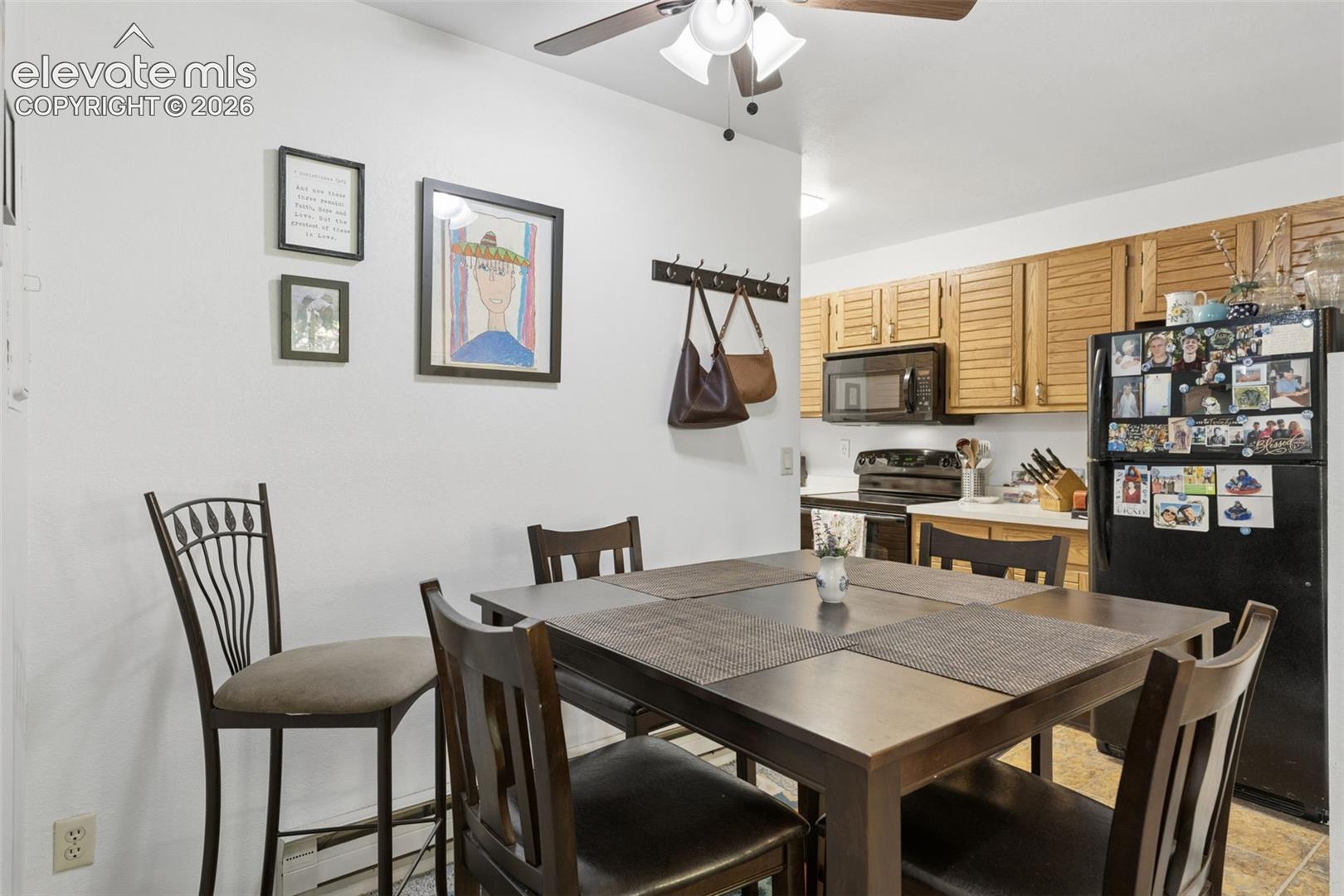 Open-concept dining area with a ceiling fan, wood-finish cabinetry, and black appliances
