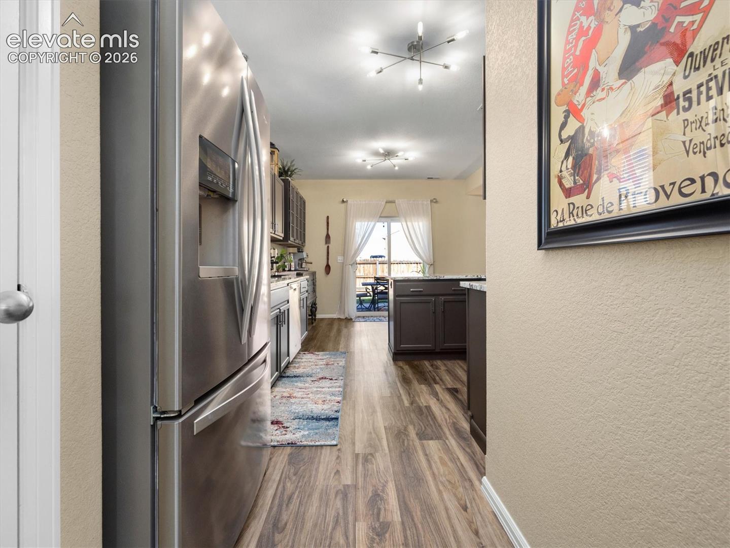 Kitchen featuring stainless steel appliances, dark wood-finish cabinetry, and LVP wood-look flooring
