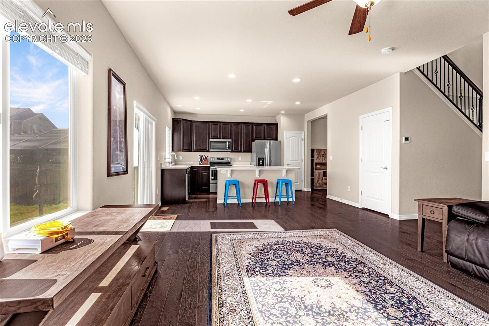 Open-concept living space with dark wood-finish flooring, recessed lighting, and a ceiling fan