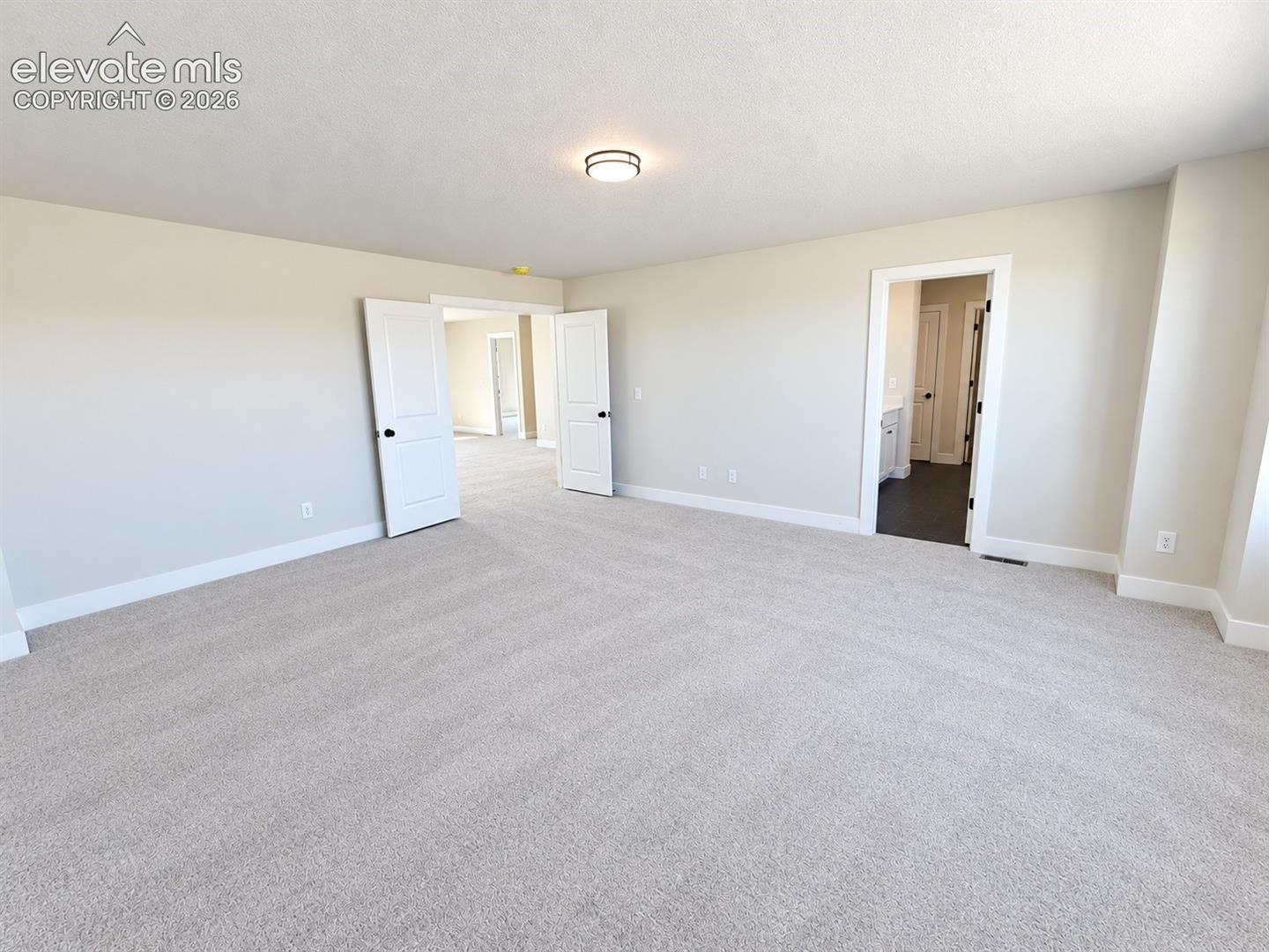 Spacious room with light neutral wall tones, plush carpeting, and recessed lighting