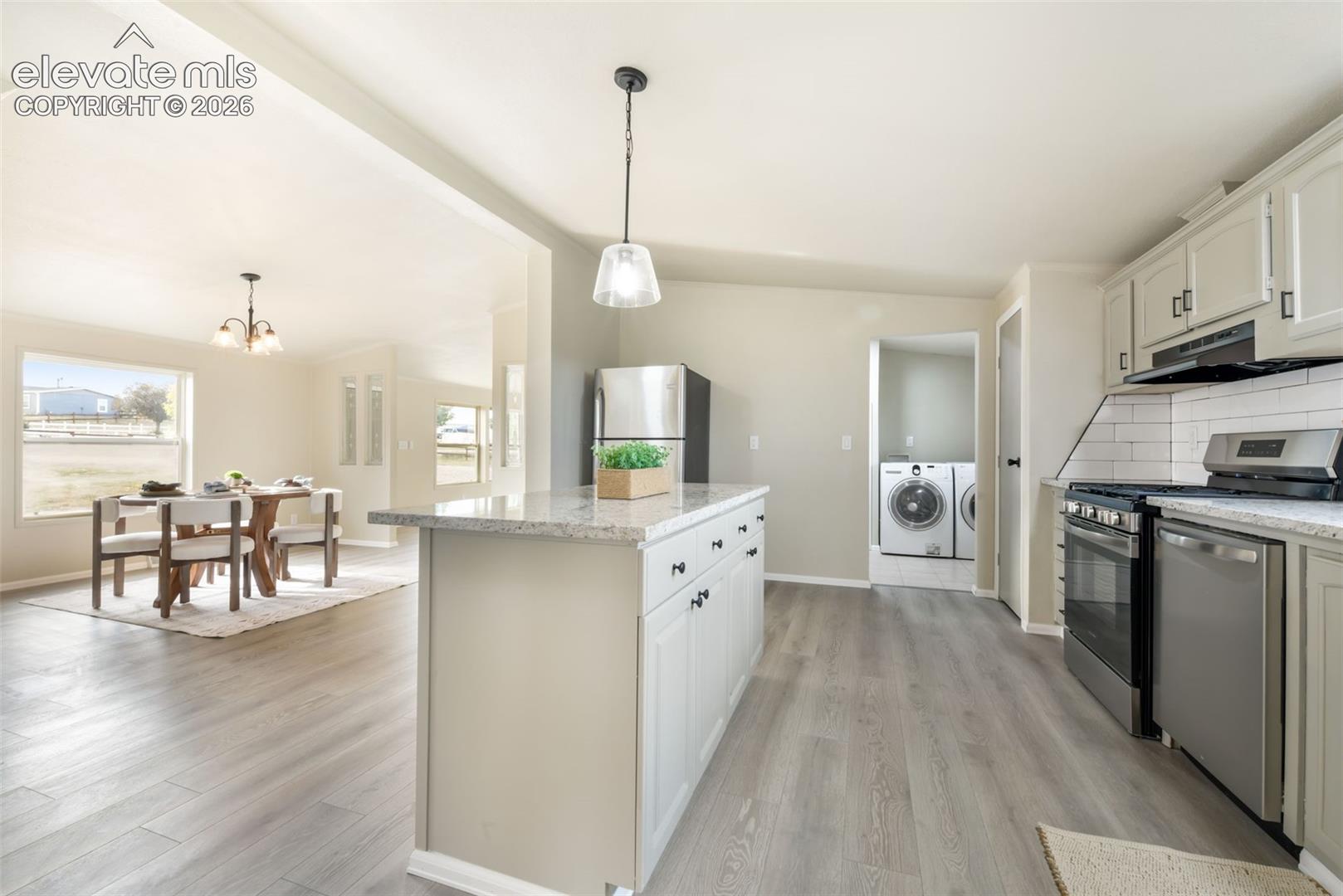 Kitchen with stainless steel appliances, light wood-finish flooring, white cabinetry, and granite countertops