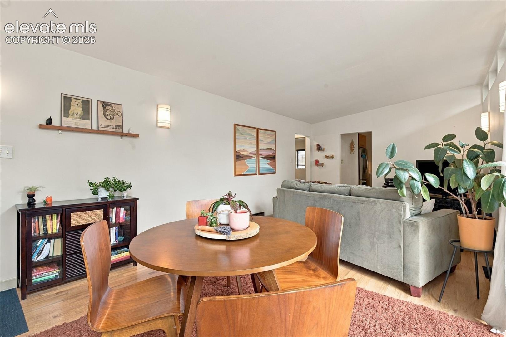 Open-concept interior featuring light wood-finish flooring, wall-mounted ambient lighting fixtures, and high-reaching ceilings