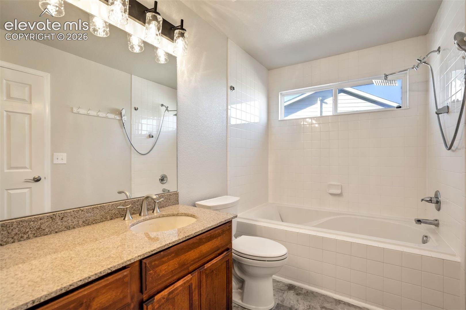 Primary bathroom with granite counters and a large tub shower. 