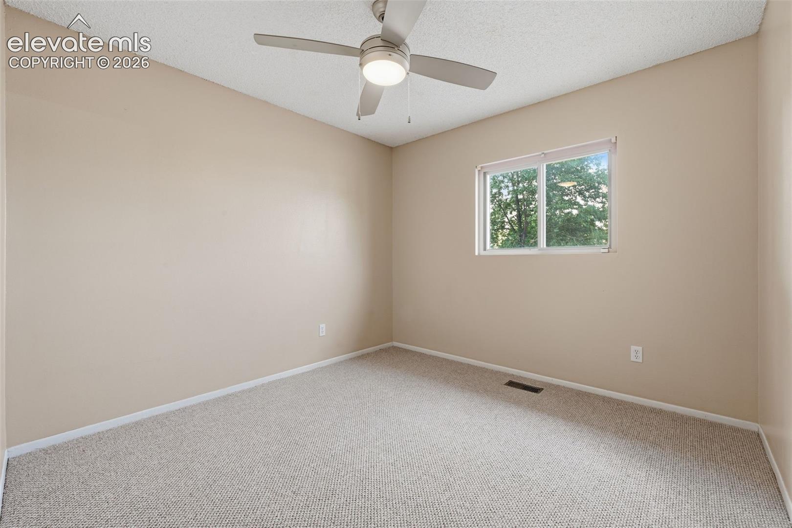 Textured ceiling, wall-to-wall carpeting, single window, and a ceiling fan with integrated lighting