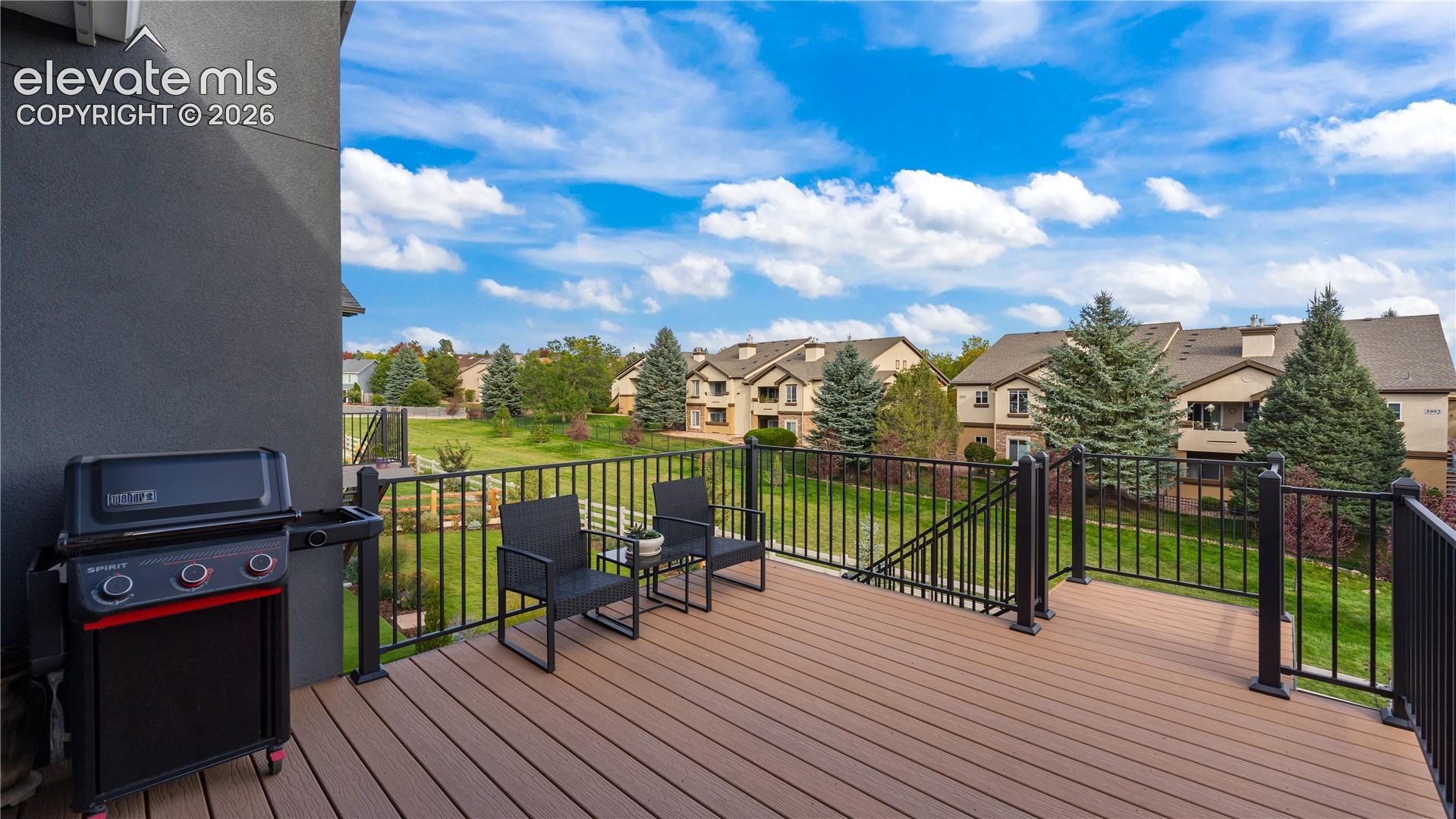 Composite deck featuring black metal railings and a staircase leading to the grass-covered grounds