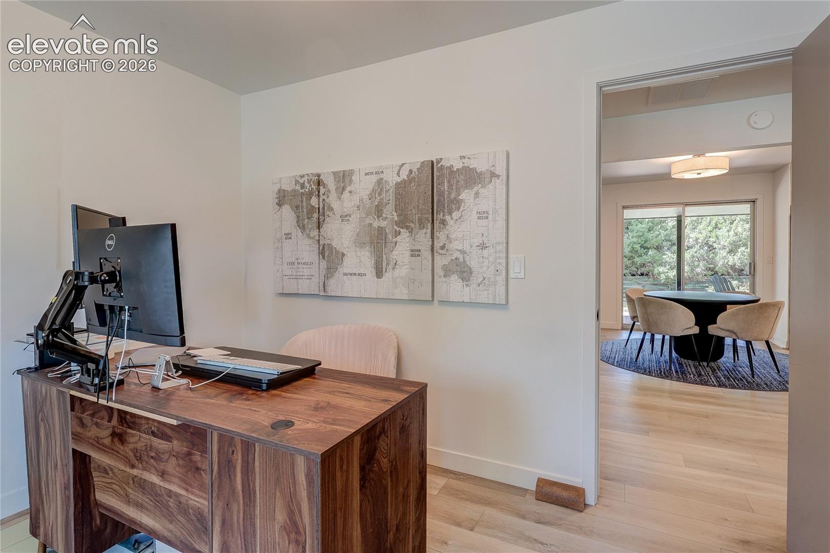 Wood-finish flooring throughout, light-toned walls, and an open doorway leading to an additional room