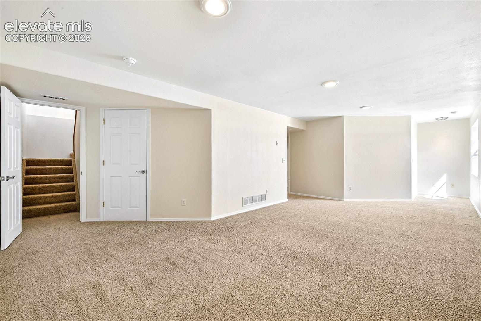 Basement Family room Expansive carpeted area with recessed lighting and a neutral color palette