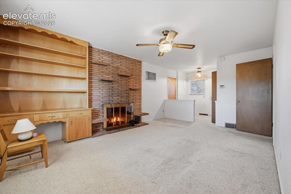 Brick fireplace with an integrated hearth, custom built-in wood shelving and cabinetry, and a ceiling-mounted light fixture