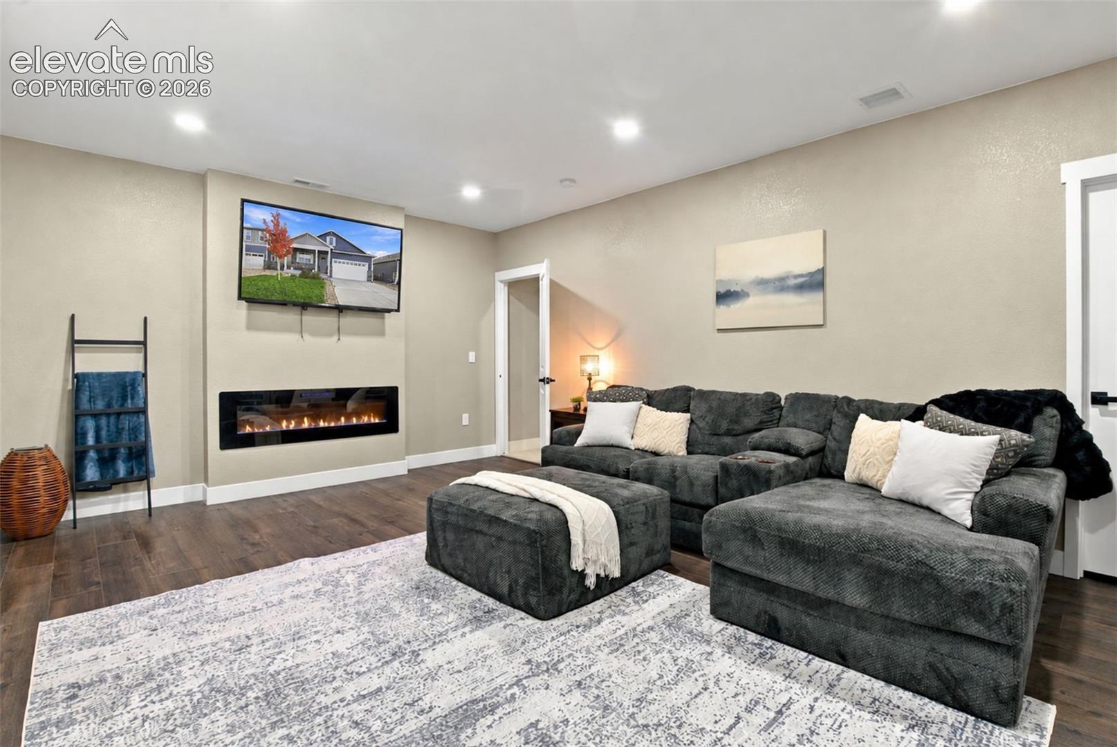 Living area featuring wood-finish flooring, recessed lighting, and a built-in wall-mounted electric fireplace